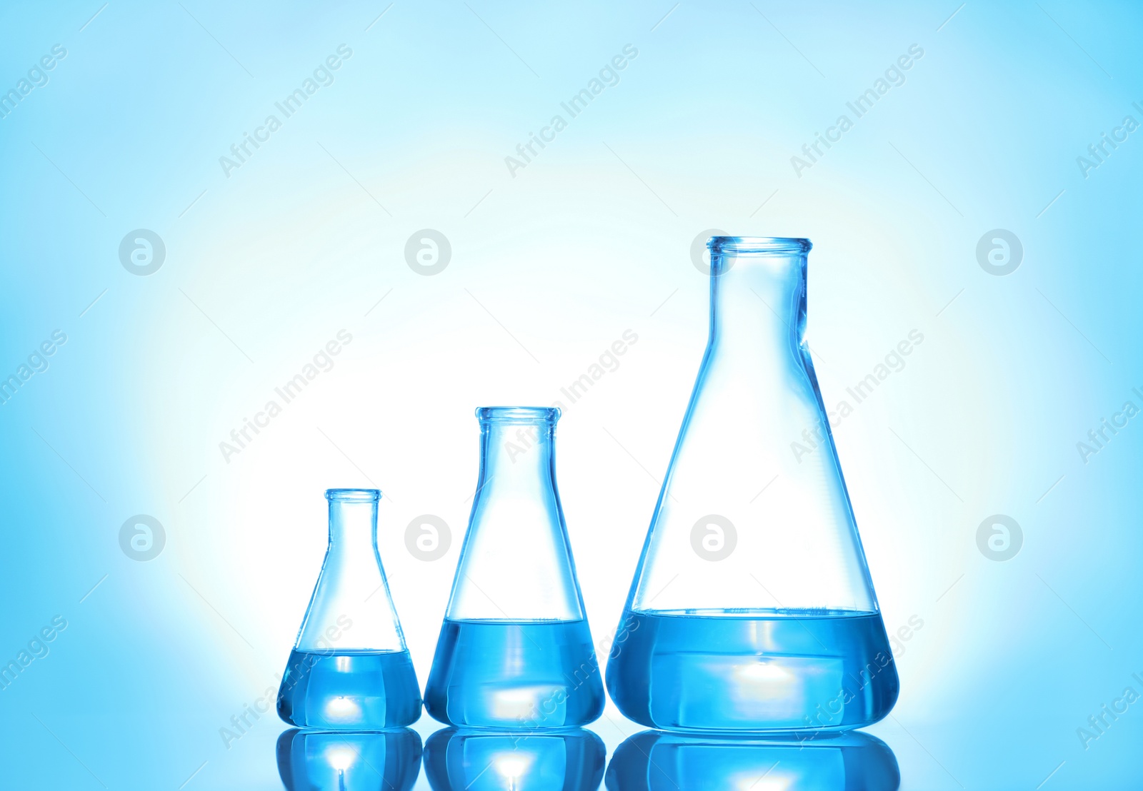 Photo of Laboratory glassware with liquid on color background. Solution chemistry