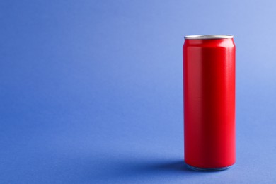 Photo of Energy drink in red can on blue background, space for text