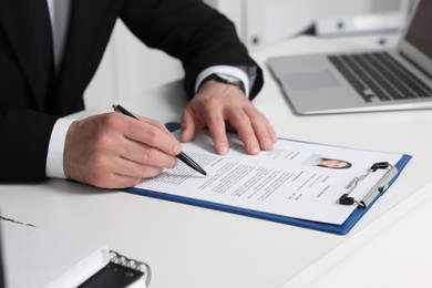 Photo of Human resources manager reading applicant's resume at table in office, closeup