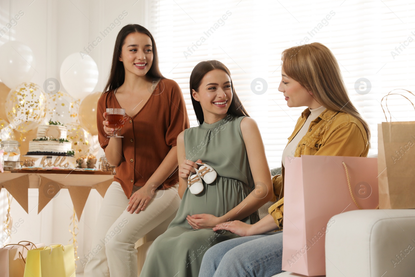 Photo of Happy pregnant woman spending time with friends at baby shower party