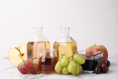 Photo of Different types of vinegar and ingredients on light marble table, closeup