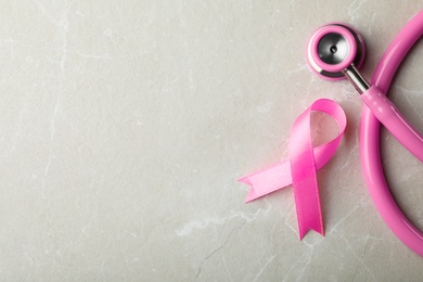 Pink ribbon and stethoscope on grey background, top view with space for text. Breast cancer concept