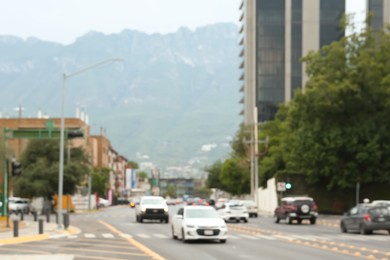 Photo of Asphalt road with modern cars near mountains, blurred view