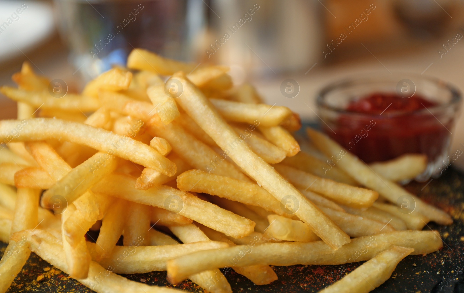 Photo of Tasty French fries with red sauce served on table in cafe, closeup