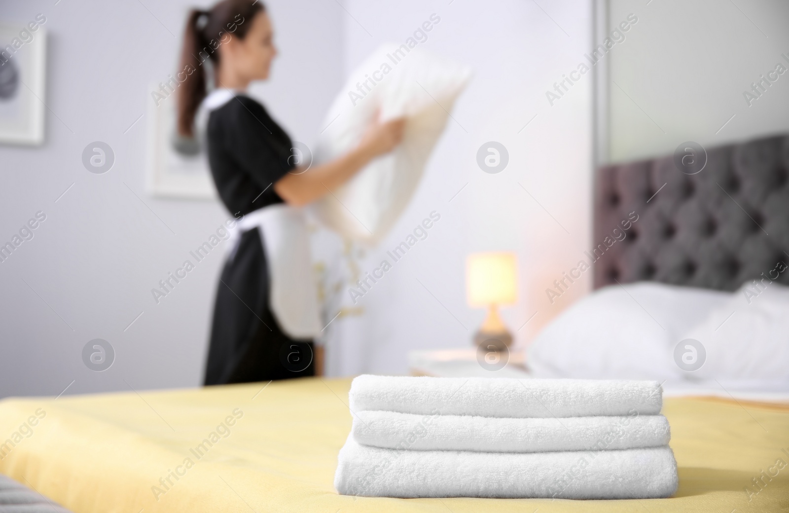 Photo of Stack of towels and blurred maid on background in hotel room