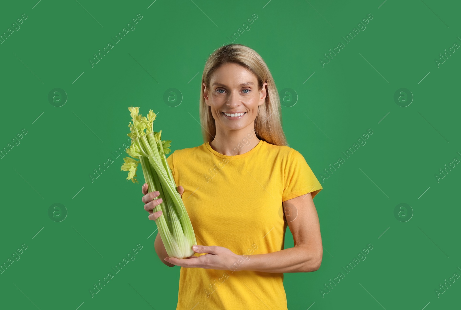 Photo of Happy woman with fresh celery bunch on green background