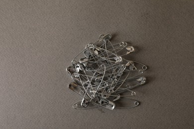 Photo of Pile of safety pins on grey textured background, flat lay