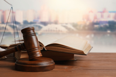 Judge's gavel and book on wooden table against beautiful cityscape 