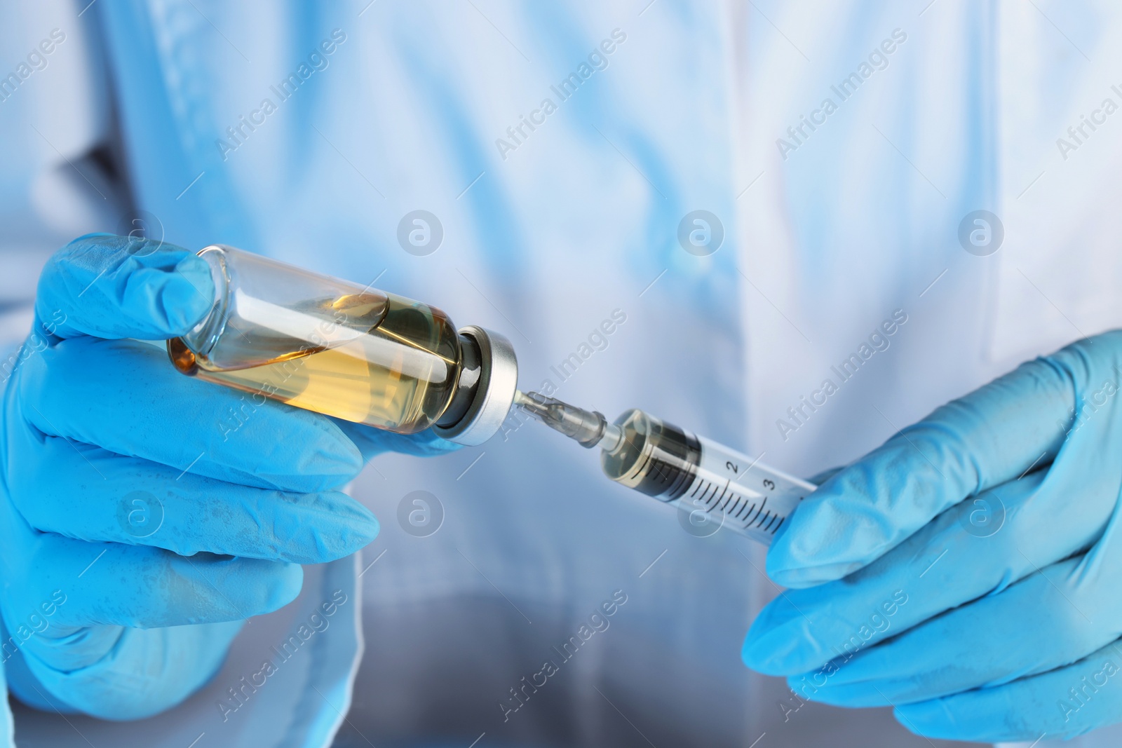 Photo of Doctor filling syringe with medication from glass vial, closeup