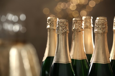 Photo of Many bottles of champagne on blurred background, closeup. Space for text