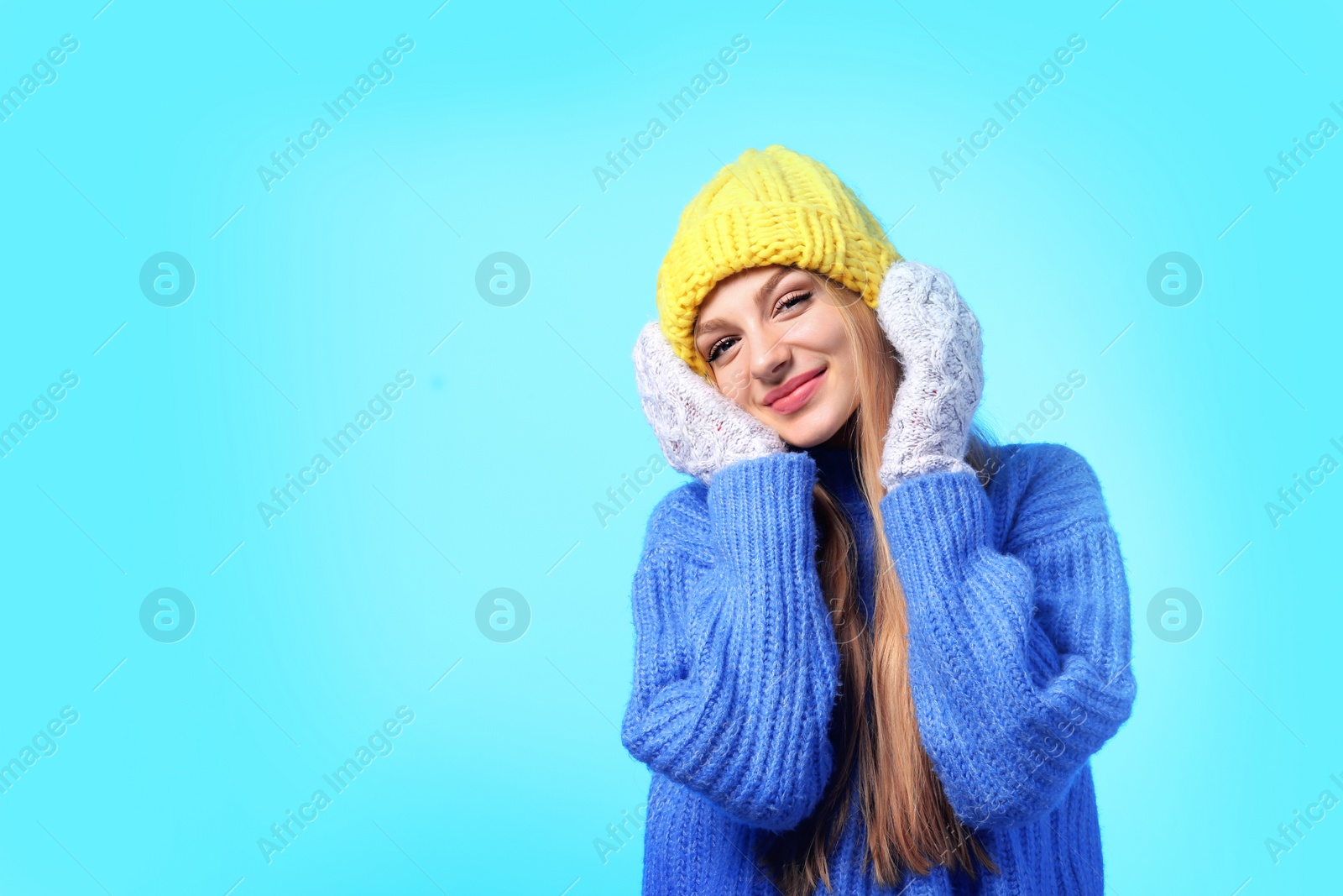 Photo of Portrait of emotional young woman in stylish hat, sweater and mittens on color background, space for text. Winter atmosphere