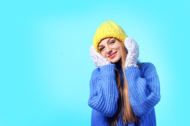 Photo of Portrait of emotional young woman in stylish hat, sweater and mittens on color background, space for text. Winter atmosphere