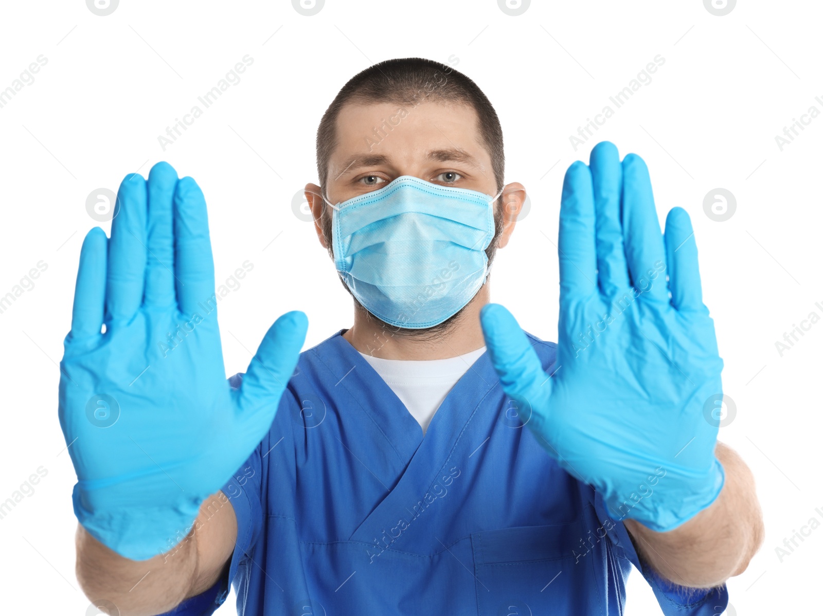 Photo of Doctor in protective mask showing stop gesture on white background. Prevent spreading of coronavirus