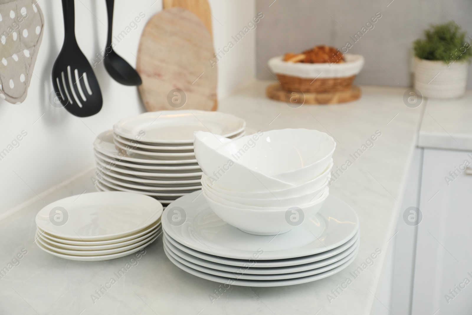 Photo of Clean plates and bowls on white marble countertop in kitchen