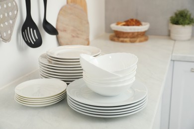 Clean plates and bowls on white marble countertop in kitchen