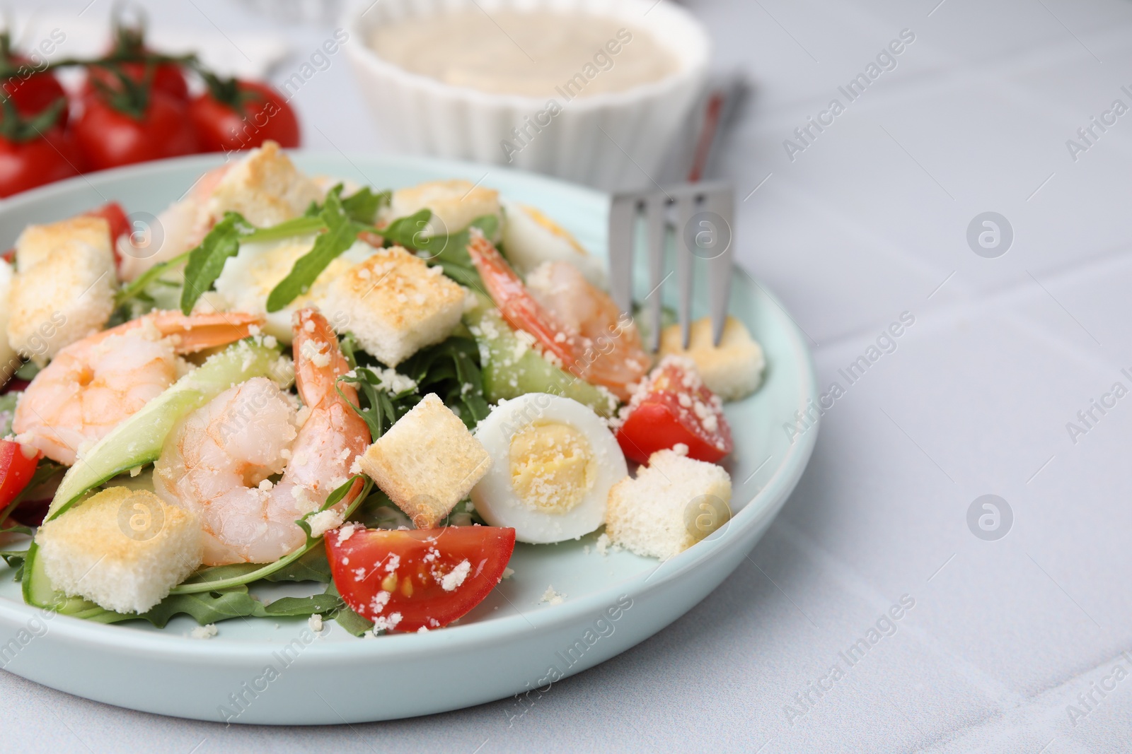 Photo of Delicious Caesar salad with shrimps on white tiled table, closeup. Space for text