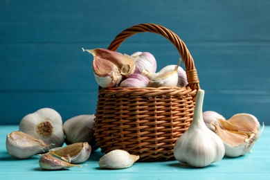 Photo of Fresh unpeeled garlic bulbs and cloves on light blue wooden table. Organic product