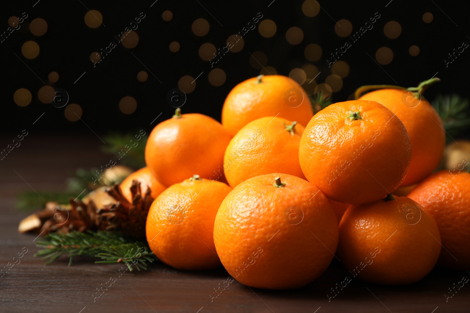 Photo of Fresh tangerines with fir tree branches on wooden table, closeup. Christmas atmosphere