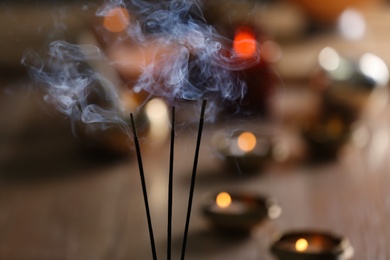 Photo of Incense sticks smoldering on blurred background, closeup