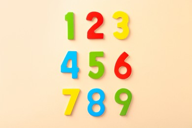 Colorful numbers on beige background, flat lay