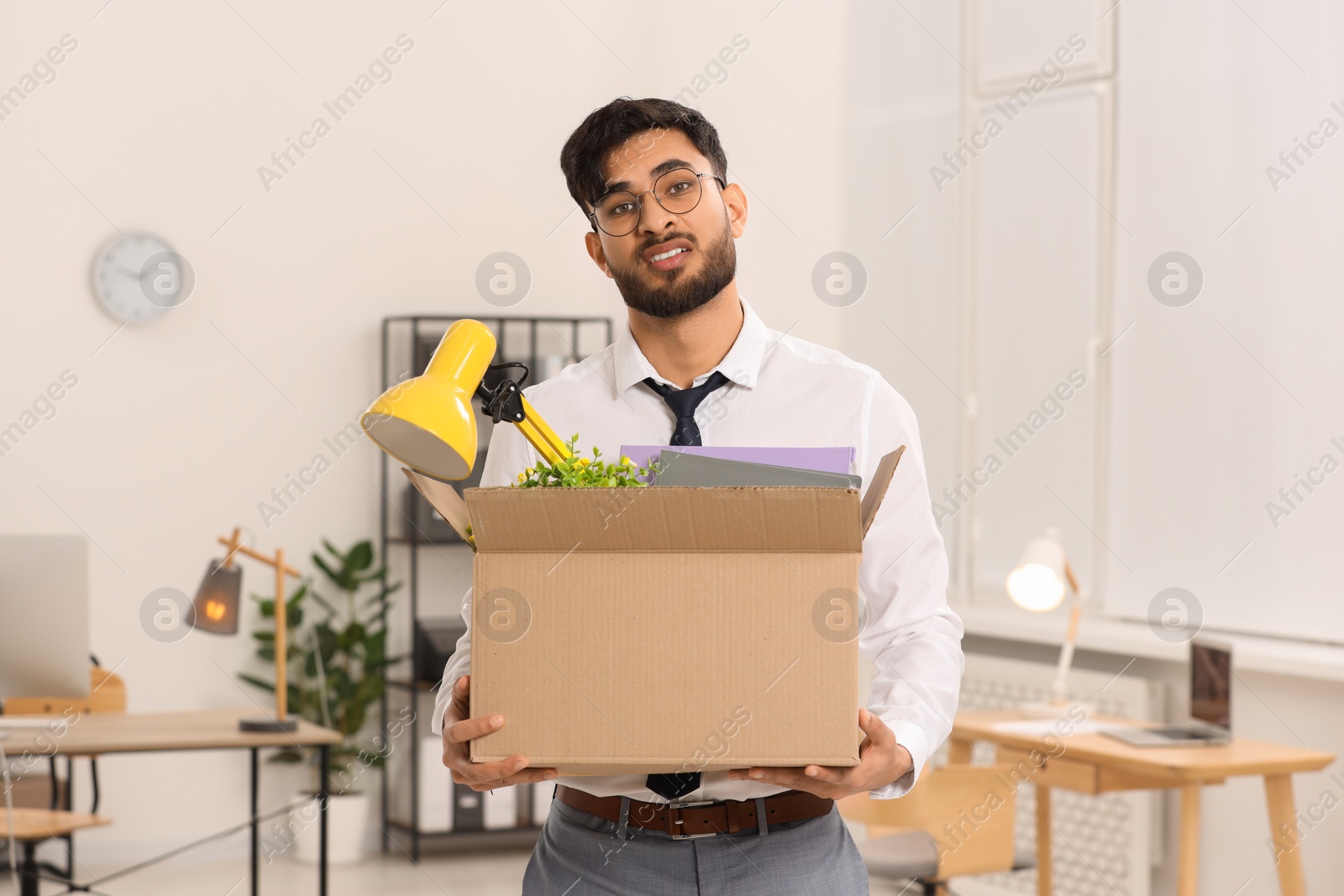 Photo of Unemployment problem. Frustrated man with box of personal belongings in office