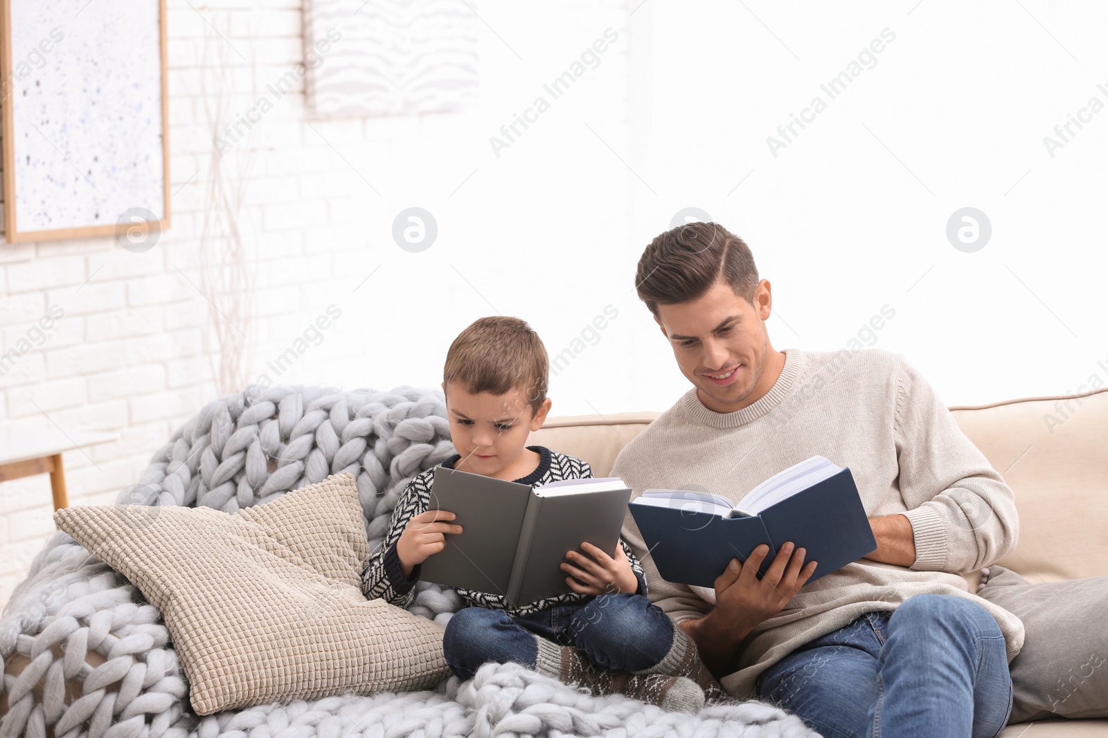 Photo of Father and his son reading books at home. Winter vacation