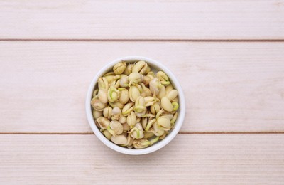 Sprouted kidney beans in bowl on white wooden table, top view