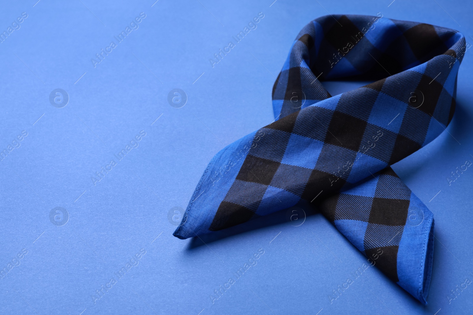 Photo of Folded bandana with check pattern on blue background. Space for text