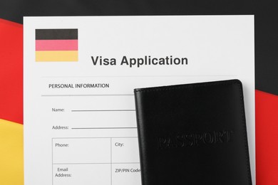 Immigration to Germany. Visa application form and passport on flag, top view