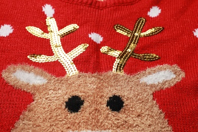 Photo of Warm red Christmas sweater with deer as background, closeup view