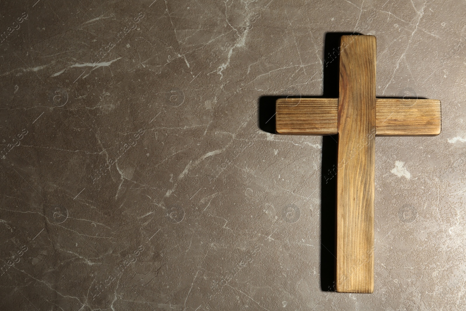Photo of Wooden Christian cross on brown marble table, top view with space for text. Religion concept