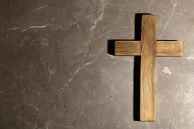 Photo of Wooden Christian cross on brown marble table, top view with space for text. Religion concept