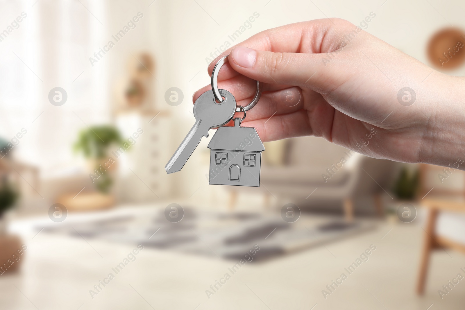 Image of Woman holding house key in room, closeup