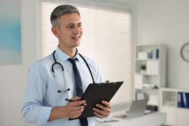 Doctor with stethoscope and clipboard in clinic, space for text