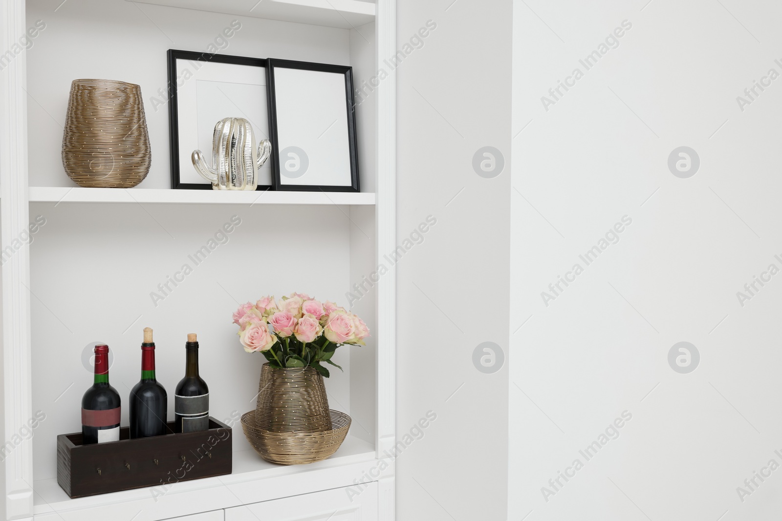 Photo of Shelves with different decor near white wall, space for text. Interior design