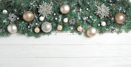 Fir tree branches with Christmas decoration on white wooden background, flat lay. Space for text