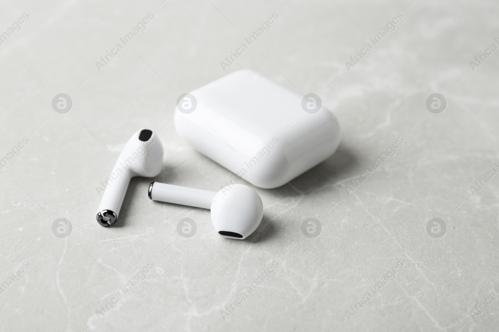 Photo of Wireless earphones and charging case on light grey marble table