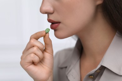 Photo of Woman taking antidepressant pill on light grey background, closeup