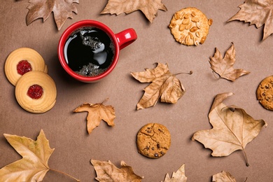 Photo of Flat lay composition with hot cozy drink and autumn leaves on color background