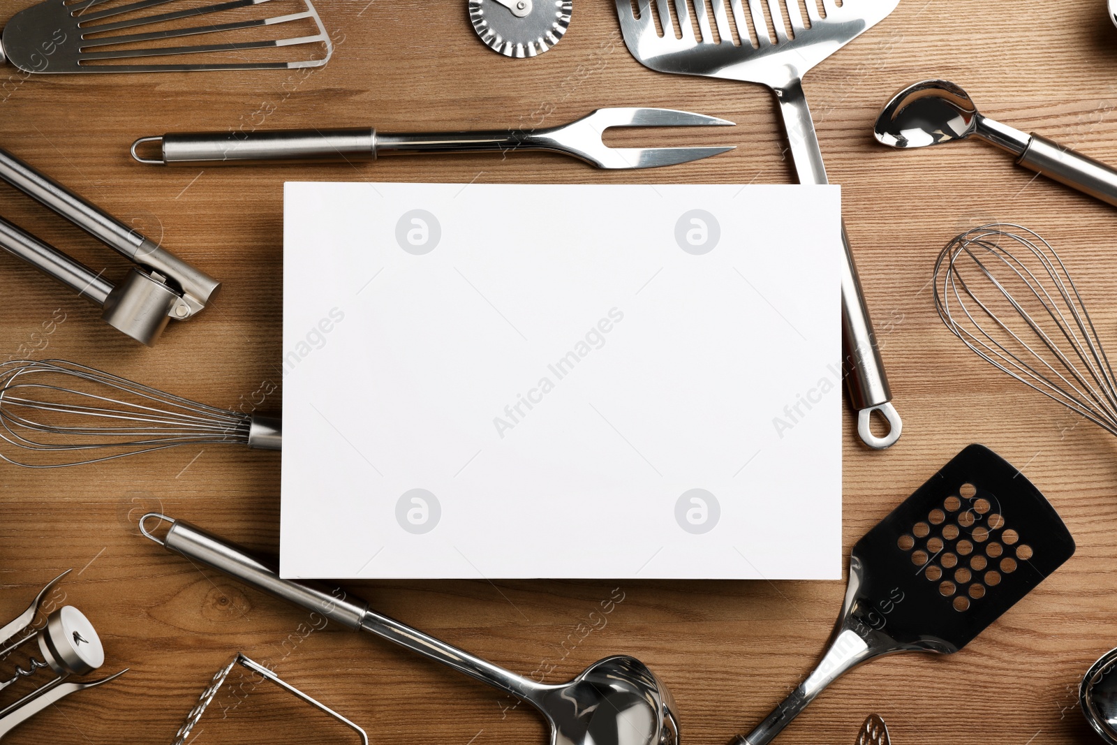 Photo of Flat lay composition with different kitchen utensils and empty card on wooden background, space for text