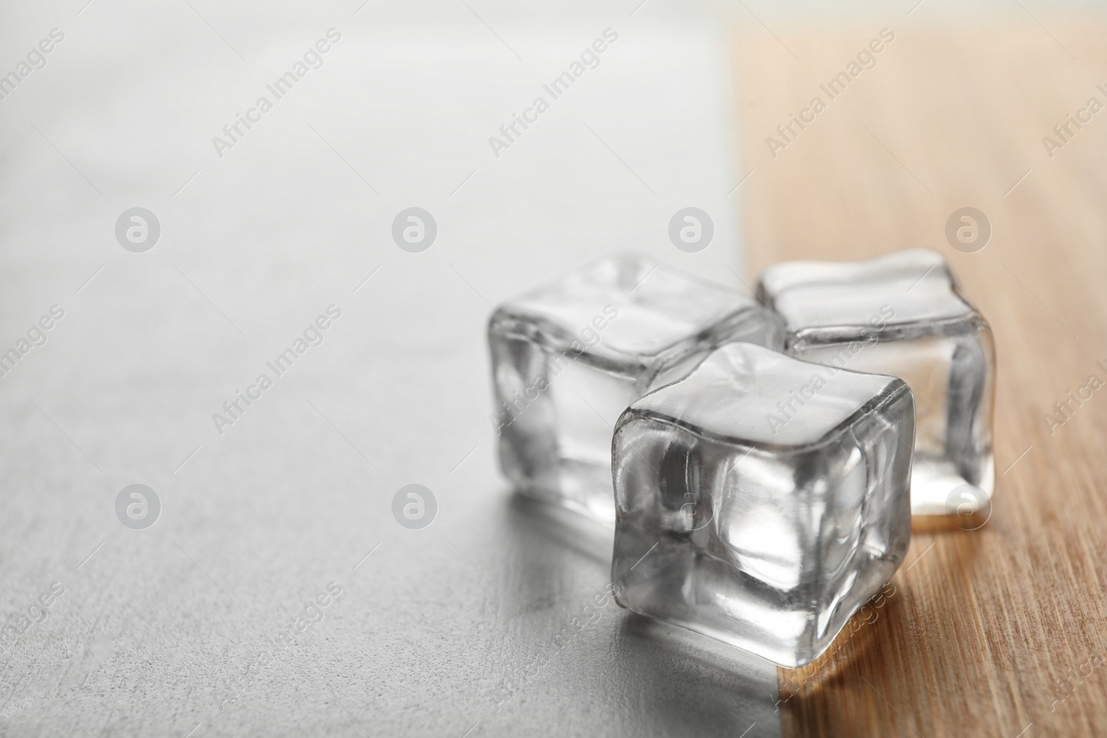 Photo of Crystal clear ice cubes on table, closeup. Space for text