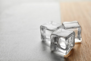 Photo of Crystal clear ice cubes on table, closeup. Space for text