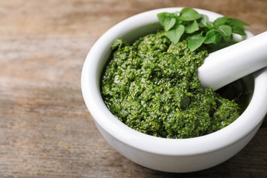 Photo of Mortar with homemade basil pesto sauce and pestle on table