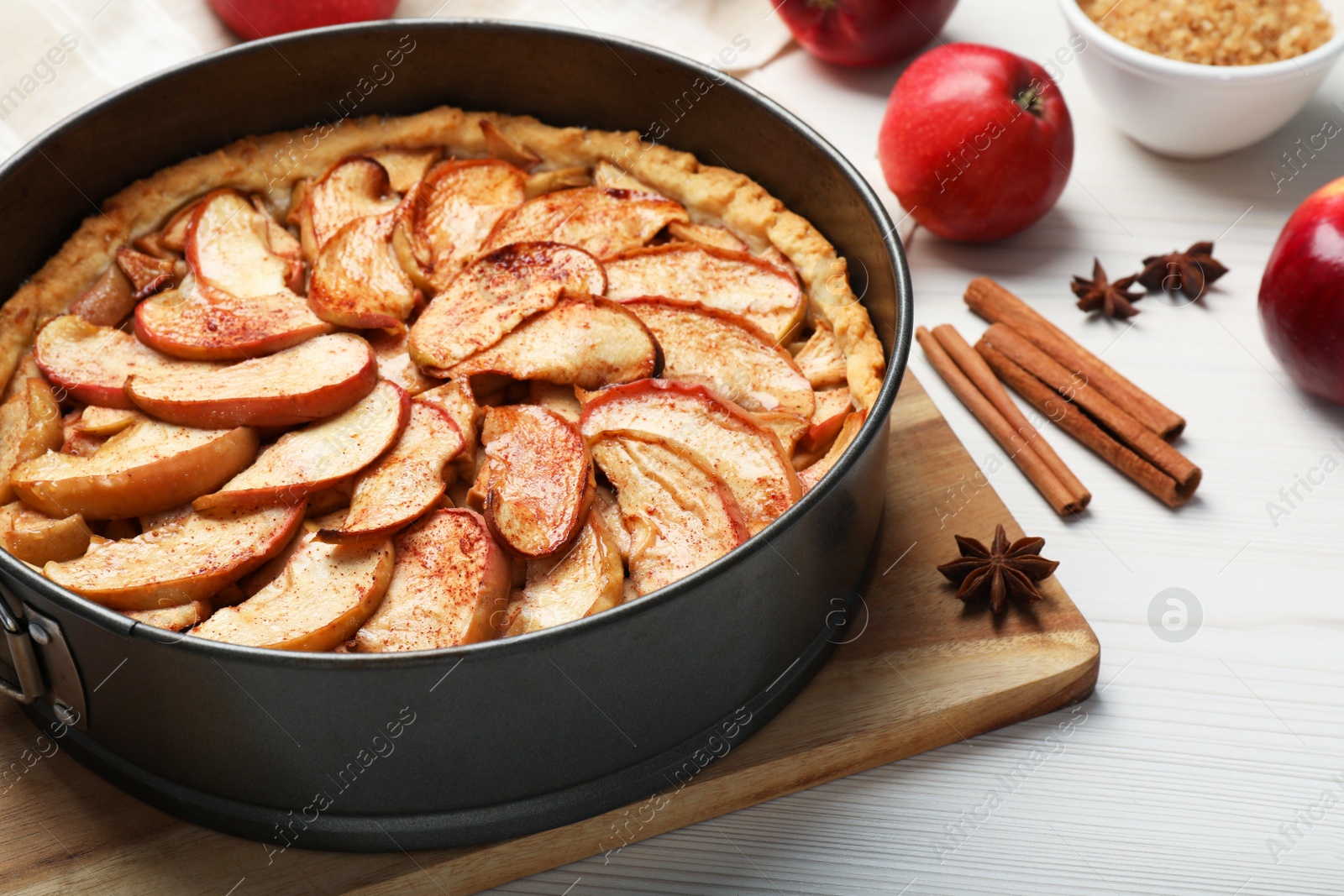 Photo of Delicious apple pie and ingredients on white wooden table