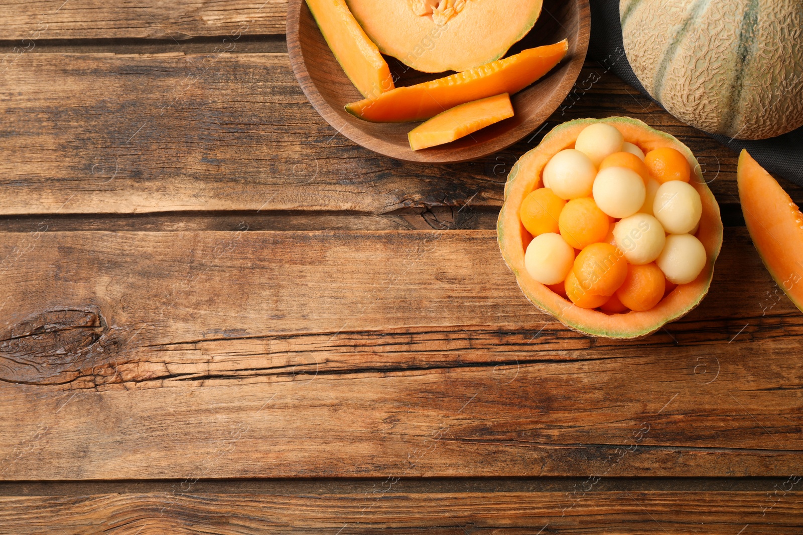 Photo of Different melon balls on wooden table, flat lay. Space for text