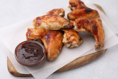 Photo of Board with marinade and chicken wings on light table, closeup