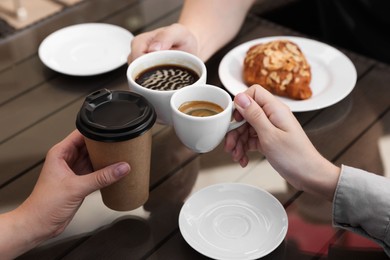 Photo of Friends drinking coffee at wooden table in outdoor cafe, closeup