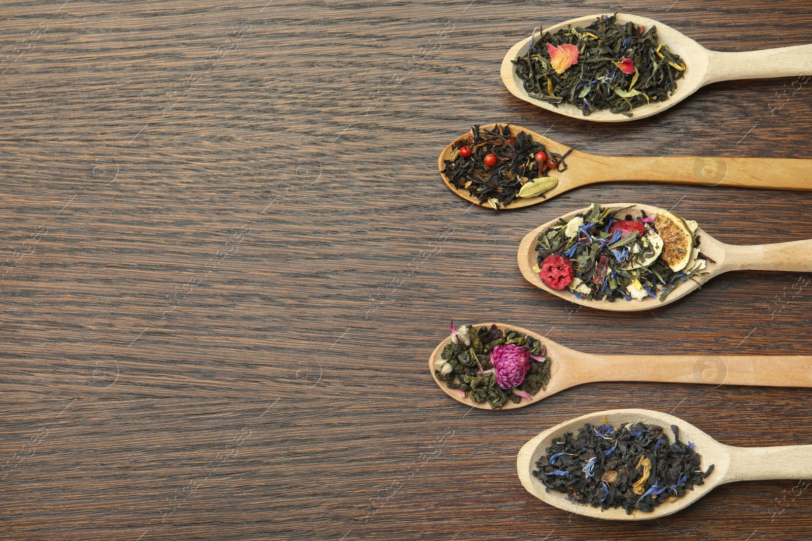 Photo of Flat composition with spoons of dried herbal tea leaves on wooden table. Space for text