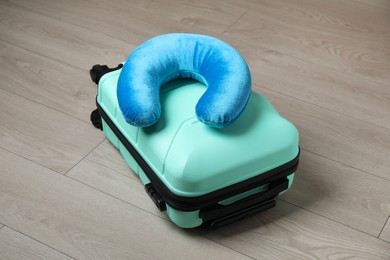 Photo of Turquoise travel pillow and suitcase on floor