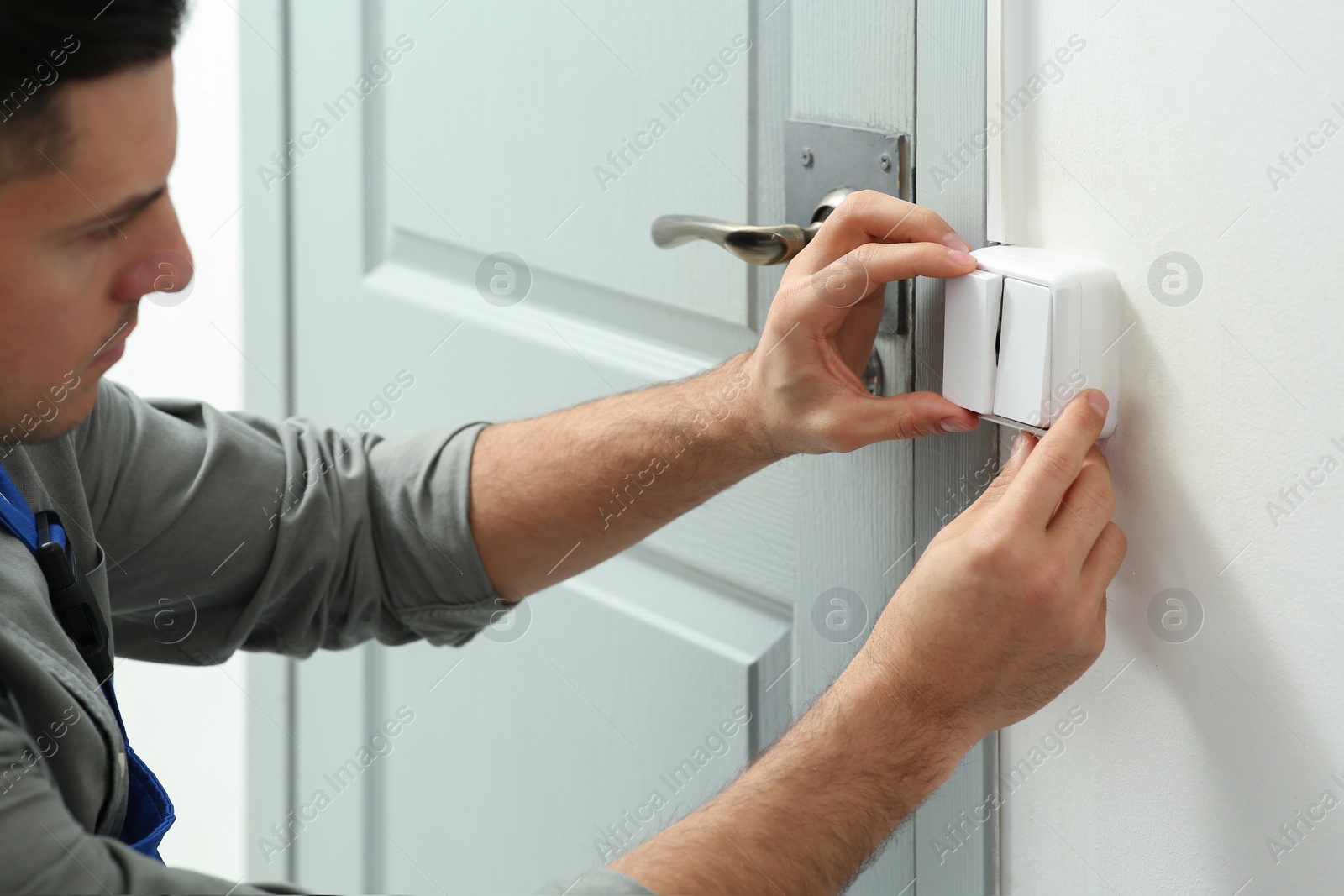 Photo of Professional electrician repairing light switch in room, closeup